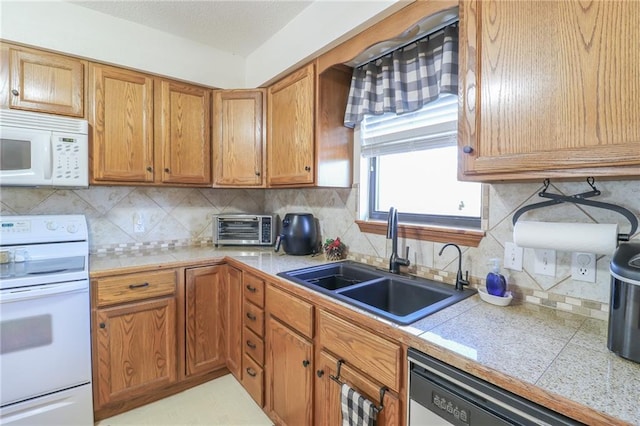 kitchen featuring white appliances, sink, and tasteful backsplash