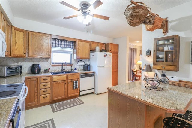 kitchen featuring sink, tasteful backsplash, kitchen peninsula, white appliances, and a breakfast bar area