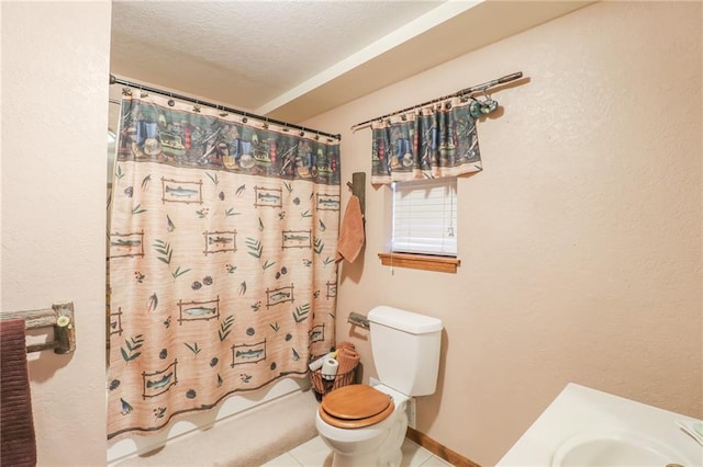 full bathroom featuring tile patterned floors, a textured ceiling, shower / tub combo with curtain, sink, and toilet