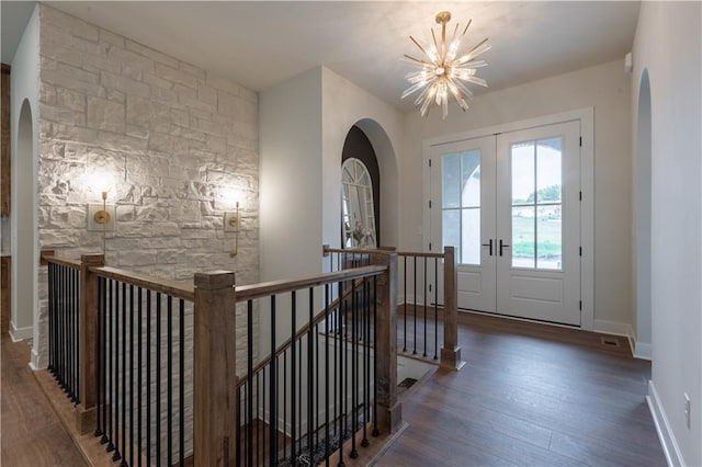 foyer entrance with a notable chandelier, dark wood-type flooring, and french doors