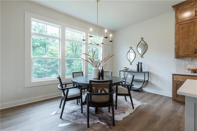 dining space with dark wood-type flooring and an inviting chandelier