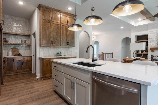 kitchen featuring dishwasher, an island with sink, pendant lighting, sink, and backsplash