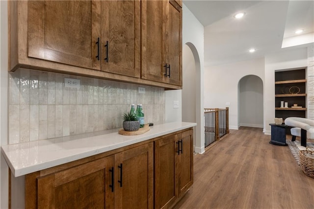 bar featuring decorative backsplash, light wood-type flooring, and built in features