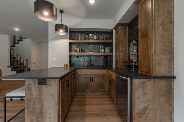 bar with decorative light fixtures, hardwood / wood-style flooring, beverage cooler, and sink