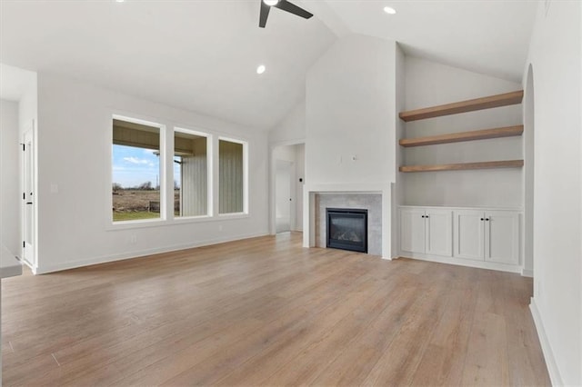 unfurnished living room featuring a fireplace, light wood-style floors, ceiling fan, high vaulted ceiling, and baseboards