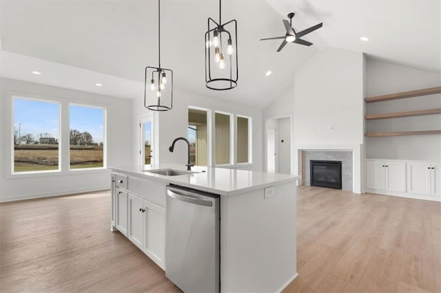 kitchen with a sink, light wood-type flooring, stainless steel dishwasher, and a glass covered fireplace