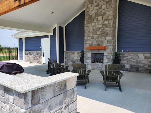 view of patio with an outdoor stone fireplace and fence