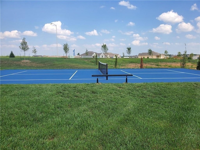 view of tennis court featuring a yard