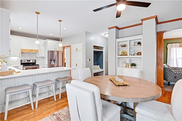 dining space featuring light hardwood / wood-style floors, ornamental molding, and ceiling fan