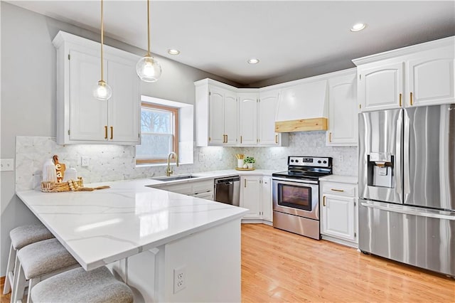 kitchen featuring custom exhaust hood, white cabinetry, stainless steel appliances, sink, and hanging light fixtures