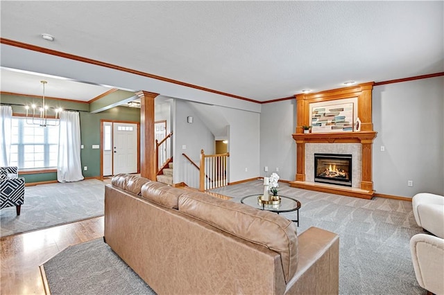 living room featuring crown molding, light hardwood / wood-style flooring, ornate columns, a fireplace, and a chandelier