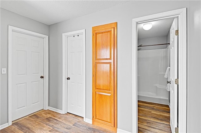 unfurnished bedroom featuring hardwood / wood-style floors, a textured ceiling, and ensuite bath