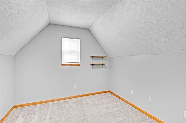 additional living space featuring carpet floors, a textured ceiling, and vaulted ceiling