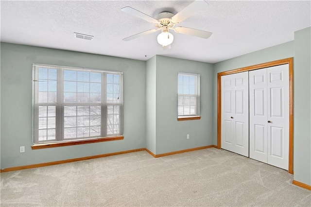 unfurnished bedroom with ceiling fan, light colored carpet, and multiple windows