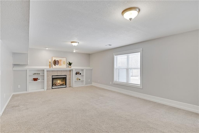 unfurnished living room with a fireplace, carpet floors, and a textured ceiling