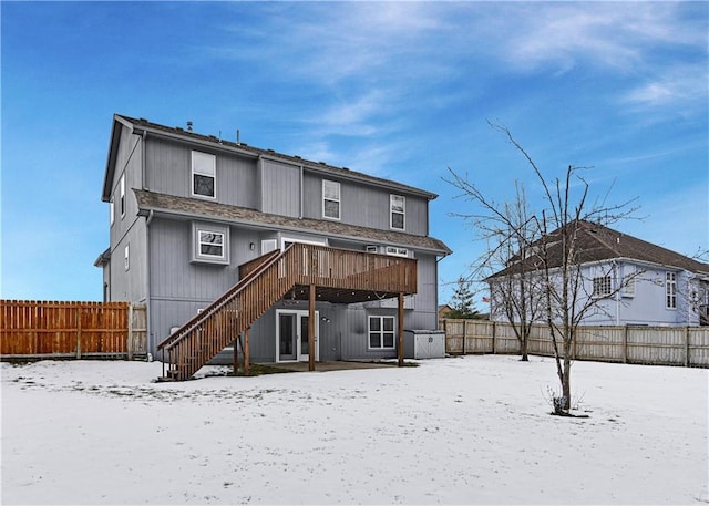 snow covered rear of property featuring a deck