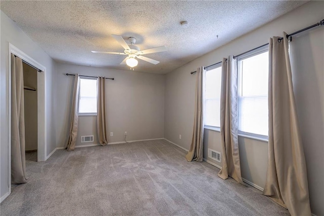 unfurnished bedroom with ceiling fan, light carpet, and a textured ceiling