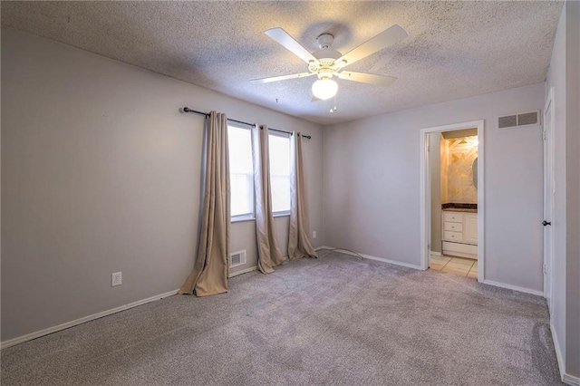 spare room with a textured ceiling, light colored carpet, and ceiling fan