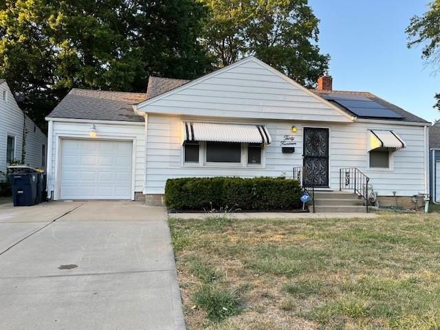 view of front of property featuring a garage, a front yard, and solar panels