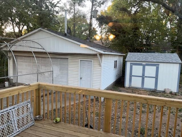 wooden terrace featuring a storage shed and a garage