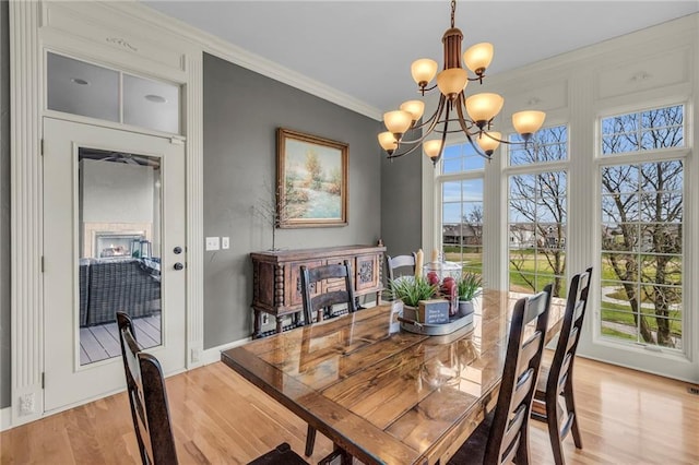 dining space featuring light wood-type flooring, crown molding, and a chandelier