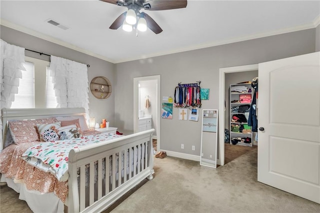 carpeted bedroom featuring ensuite bath, ceiling fan, crown molding, and a walk in closet