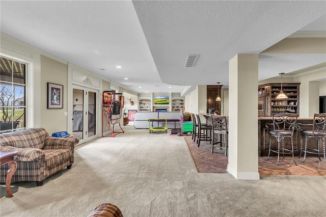 recreation room featuring carpet flooring, ornamental molding, a textured ceiling, and indoor bar