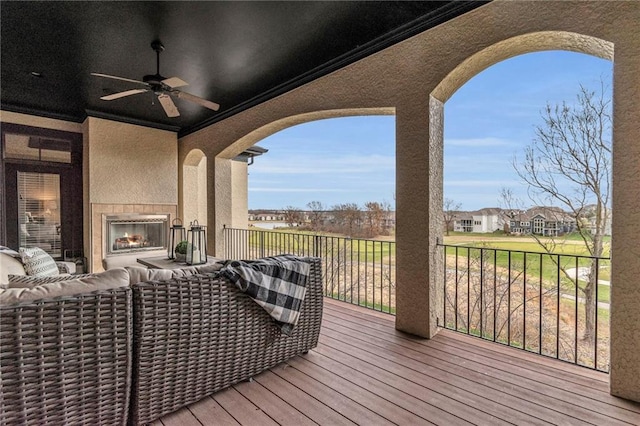 deck featuring an outdoor living space with a fireplace and ceiling fan