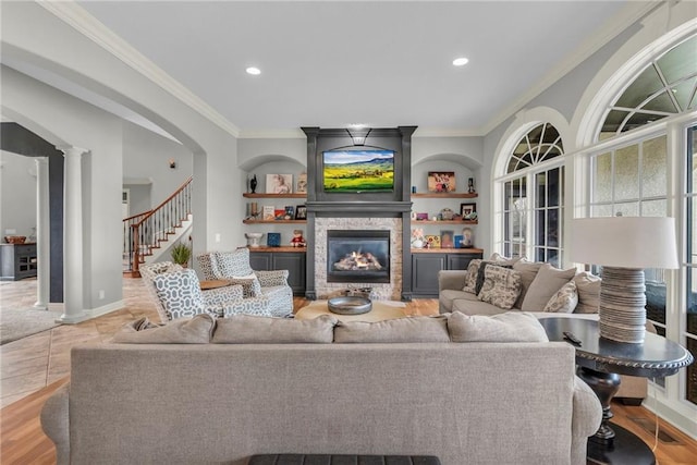 living room with a fireplace, light tile patterned floors, built in features, and crown molding