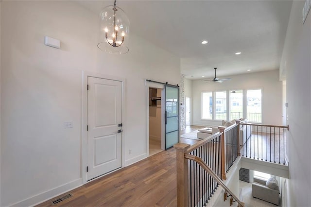 hallway with hardwood / wood-style floors, a barn door, and an inviting chandelier