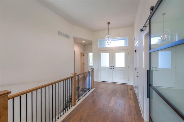 foyer featuring french doors, dark wood-type flooring, and a notable chandelier