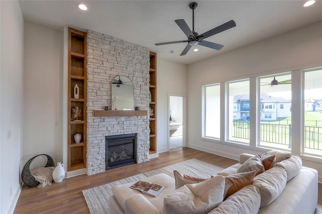 living room with hardwood / wood-style floors, built in features, and a fireplace