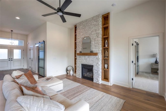 living room featuring french doors, ceiling fan, built in shelves, a fireplace, and dark hardwood / wood-style flooring