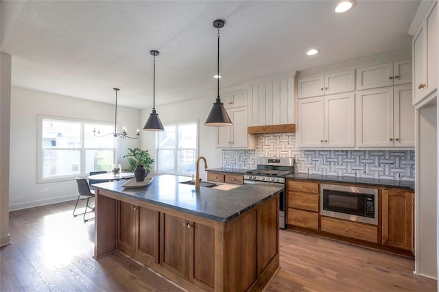 kitchen featuring sink, an island with sink, appliances with stainless steel finishes, white cabinetry, and wood-type flooring