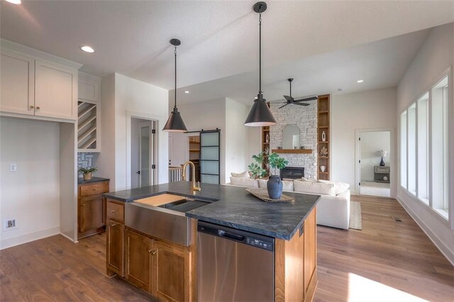 kitchen with white cabinetry, dishwasher, sink, hardwood / wood-style floors, and a kitchen island with sink