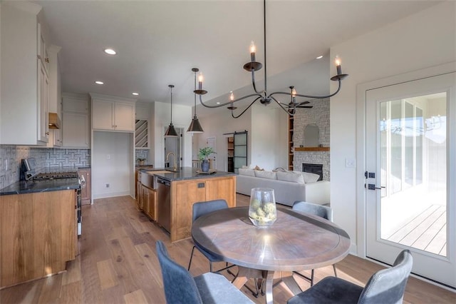 dining space with sink, light wood-type flooring, a fireplace, and an inviting chandelier