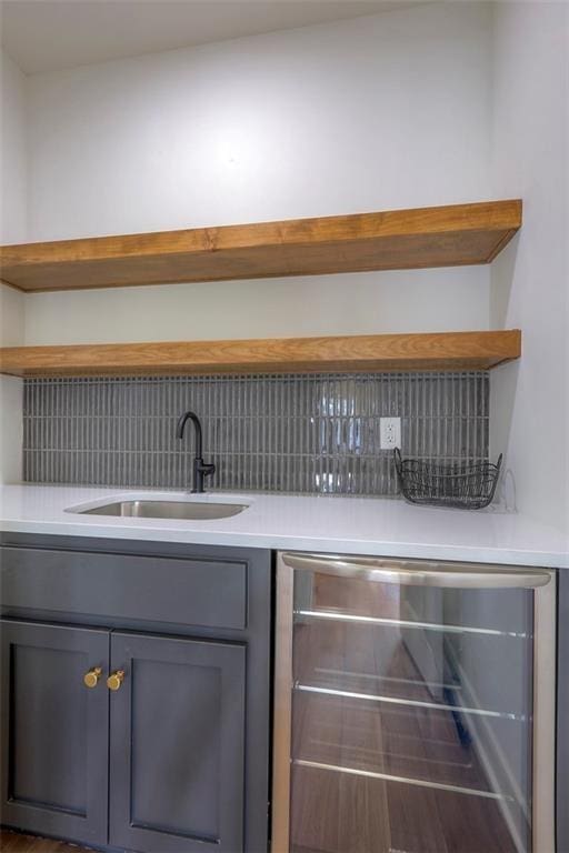 bar featuring backsplash, gray cabinets, wine cooler, and sink