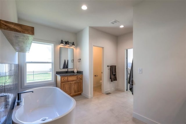 bathroom with vanity, a bathtub, and toilet