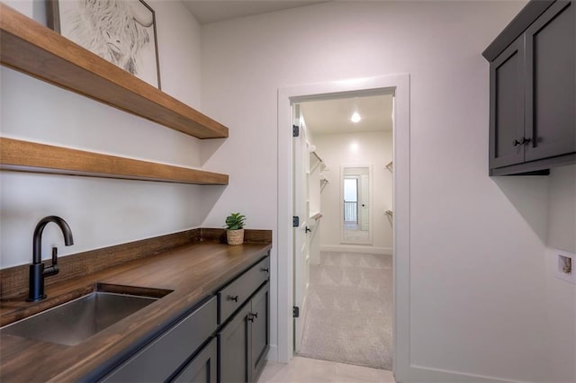 interior space featuring light colored carpet, gray cabinetry, and sink