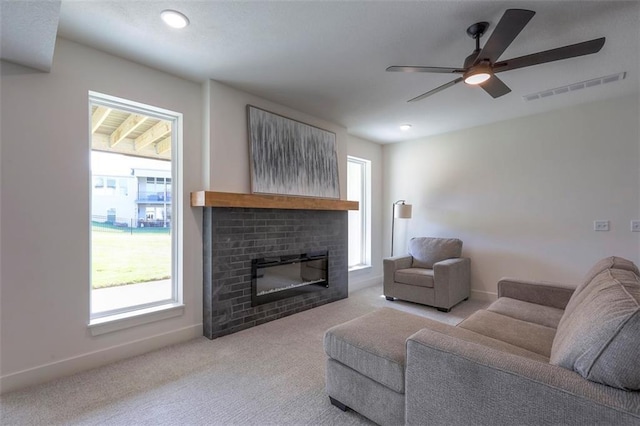 carpeted living room featuring ceiling fan and a fireplace