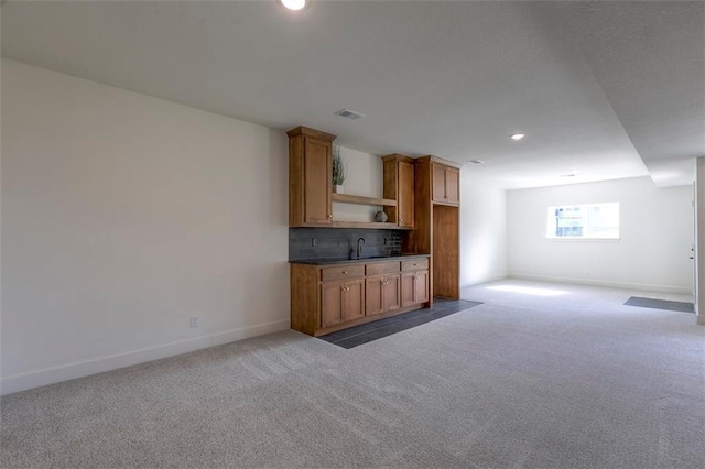 interior space with sink, carpet floors, and backsplash