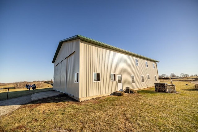 view of side of home with an outbuilding, a yard, and central AC