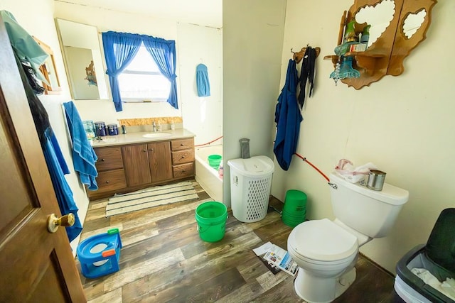 bathroom featuring a tub, vanity, wood-type flooring, and toilet