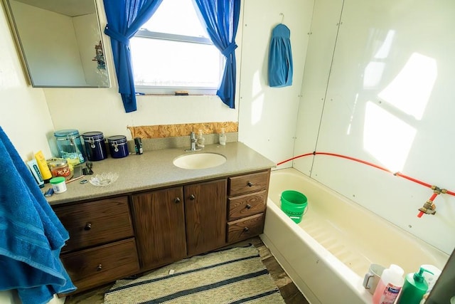 bathroom featuring wood-type flooring, vanity, and a tub to relax in