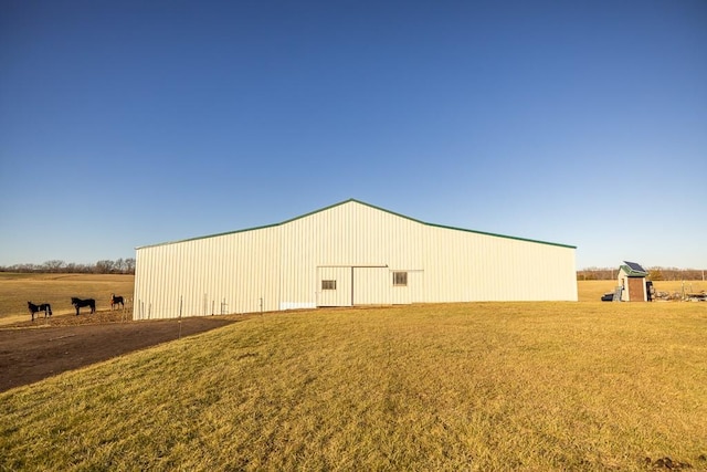 view of side of home with a rural view, an outbuilding, and a yard