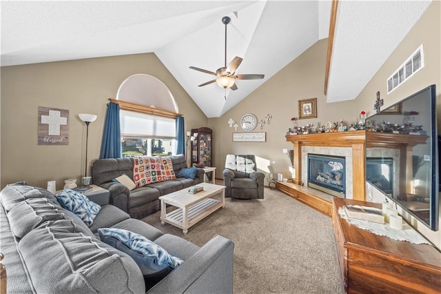 living room featuring carpet floors, lofted ceiling, a tiled fireplace, and ceiling fan