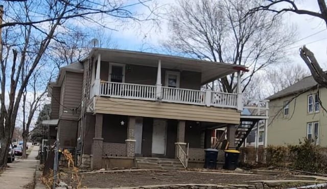 view of front of house with brick siding, a porch, and stairs