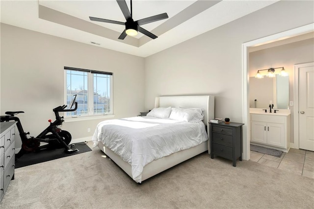 carpeted bedroom featuring a tray ceiling, ensuite bath, ceiling fan, and sink