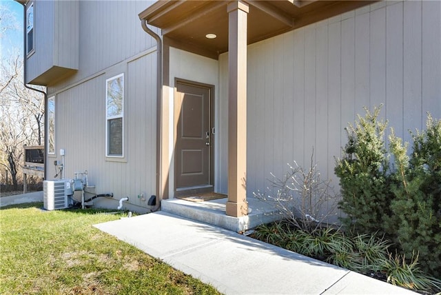 view of exterior entry featuring a yard and central AC unit