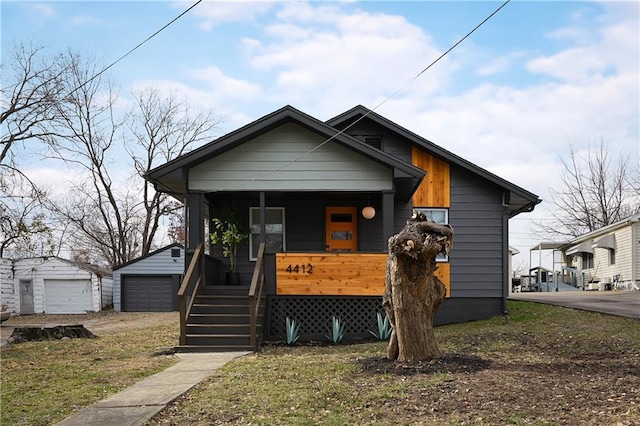 bungalow-style house featuring a porch, a garage, and an outbuilding